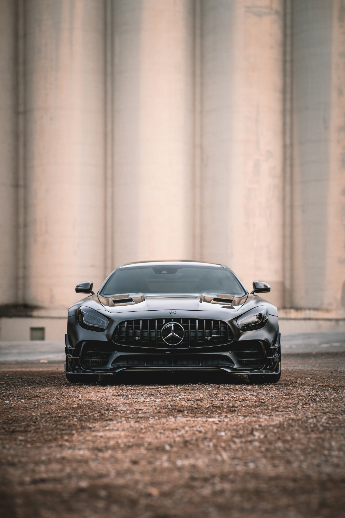 Black Mercedes sports car parked in front of concrete pillars