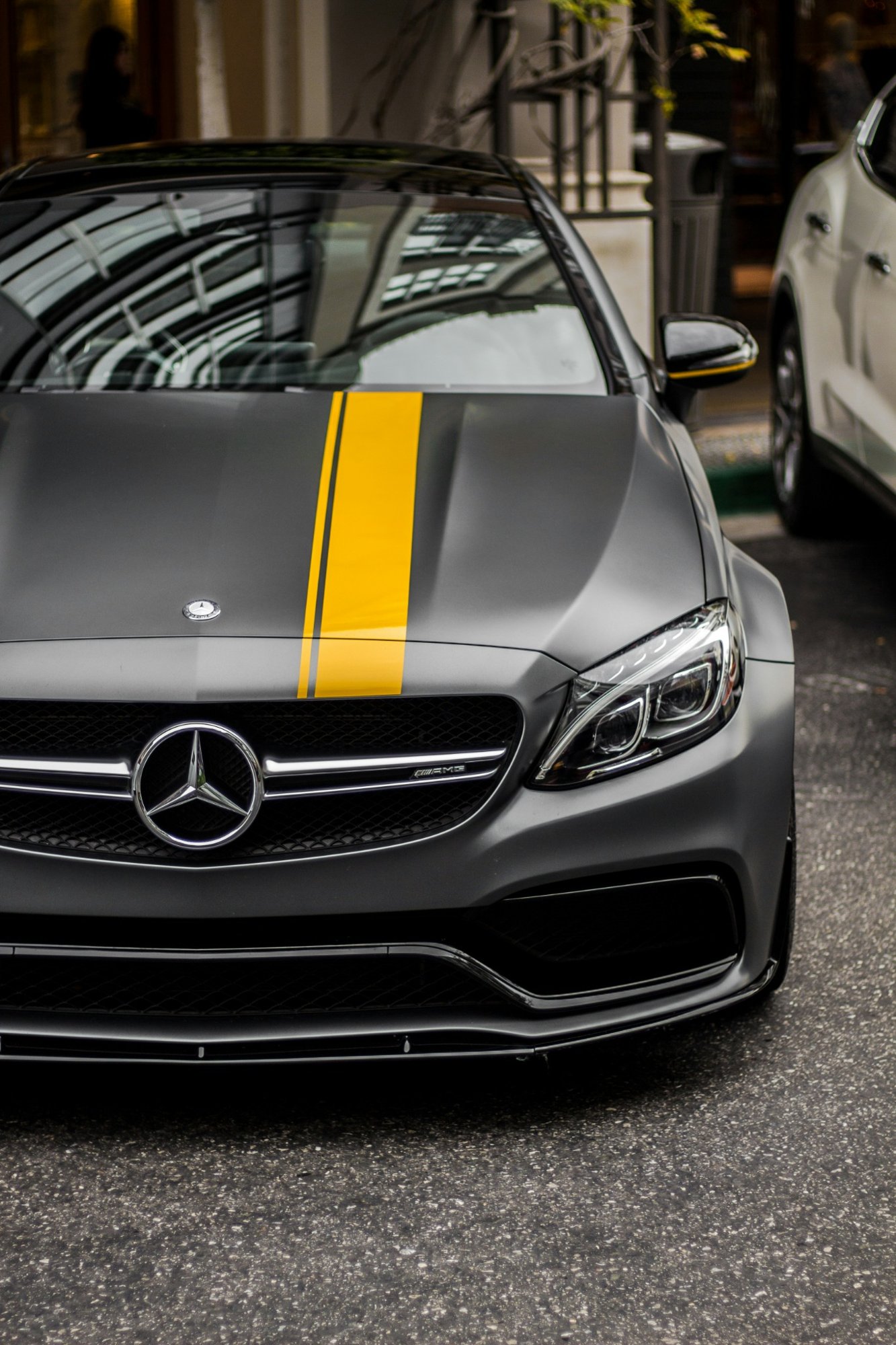 Mercedes AMG sports car with matte grey finish and yellow racing stripe parked outdoors